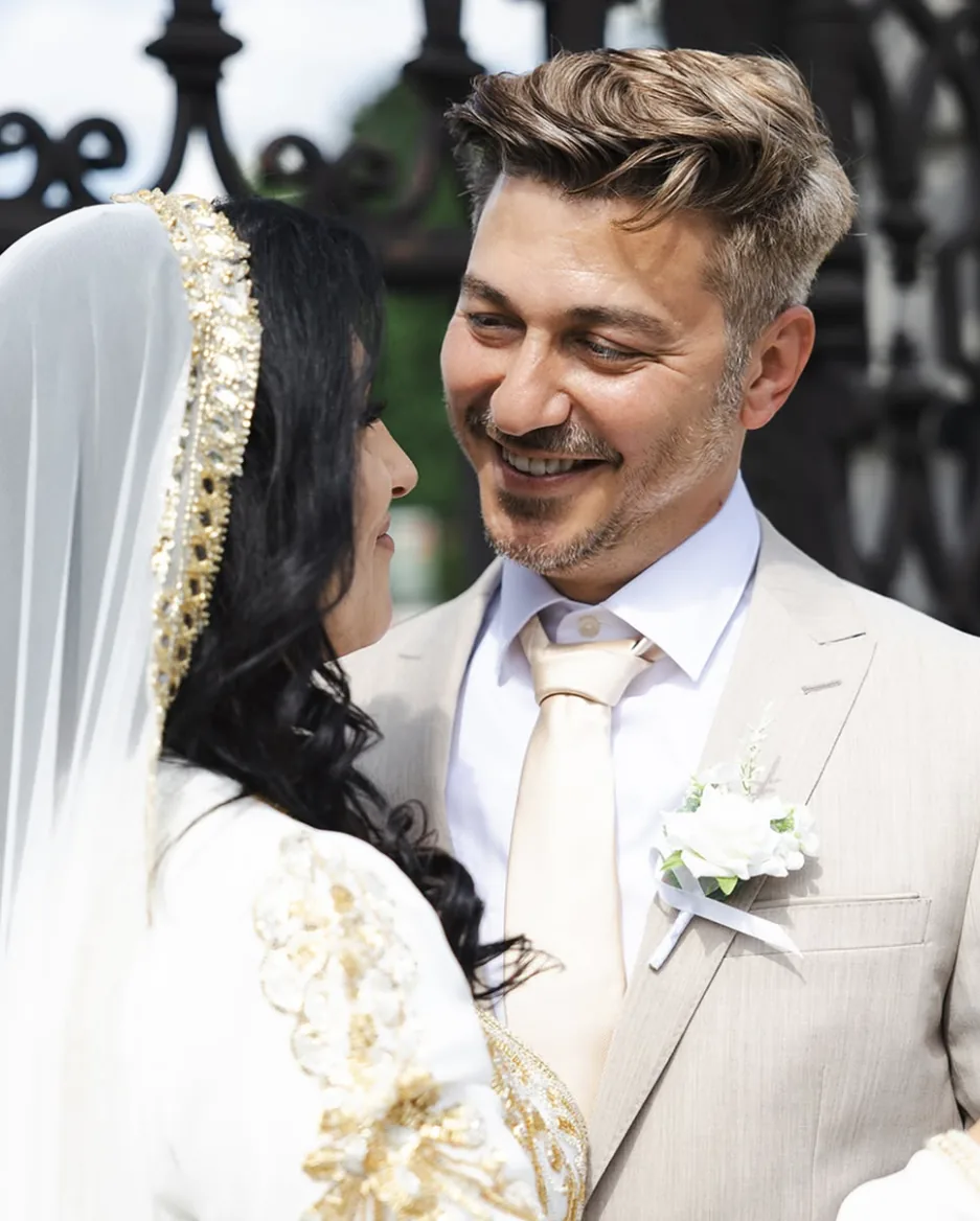 Bräutigam lächelt seine Braut im goldbestickten Brautkleid an